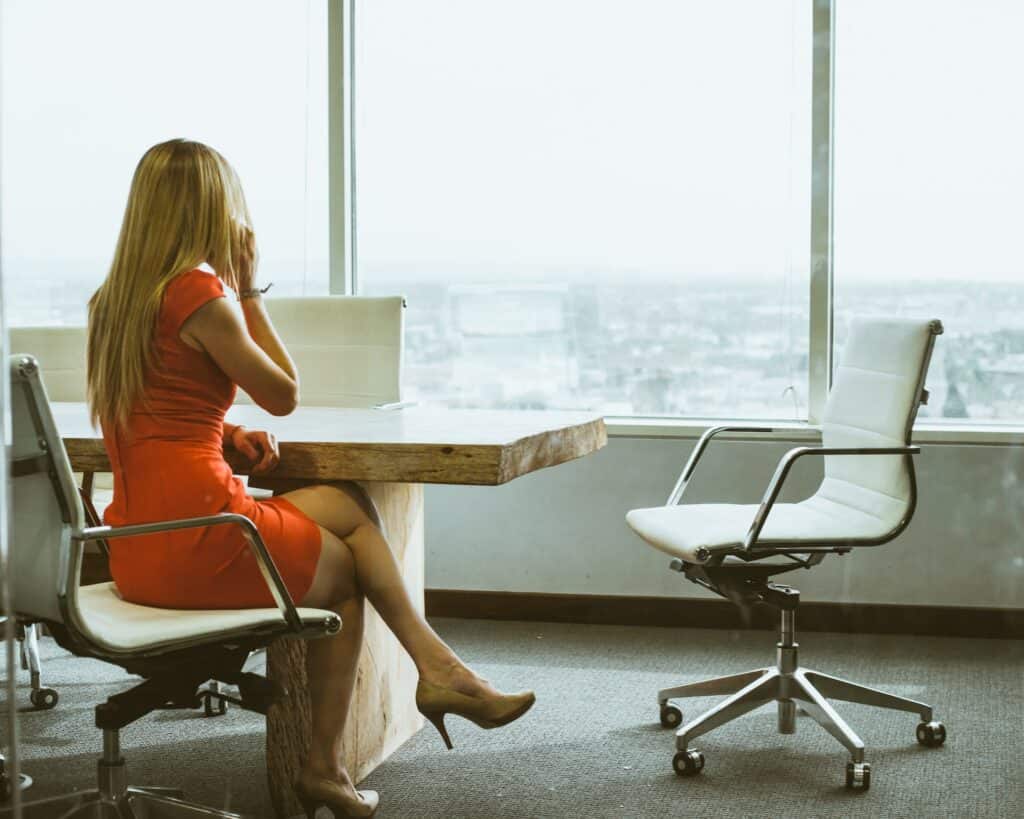 a woman in a red dress sitting in an office on a phone