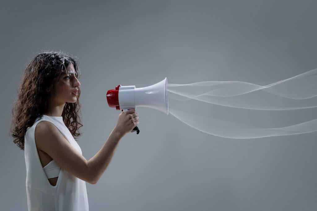 Woman holding up a megaphone with sound waves coming out of it