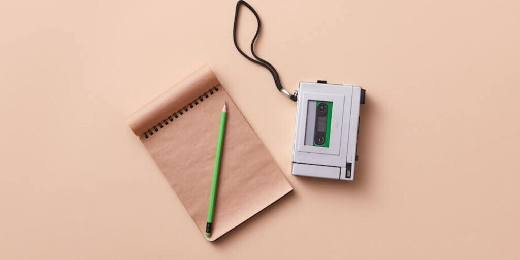 Voice recorder and a blank notebook with a pencil